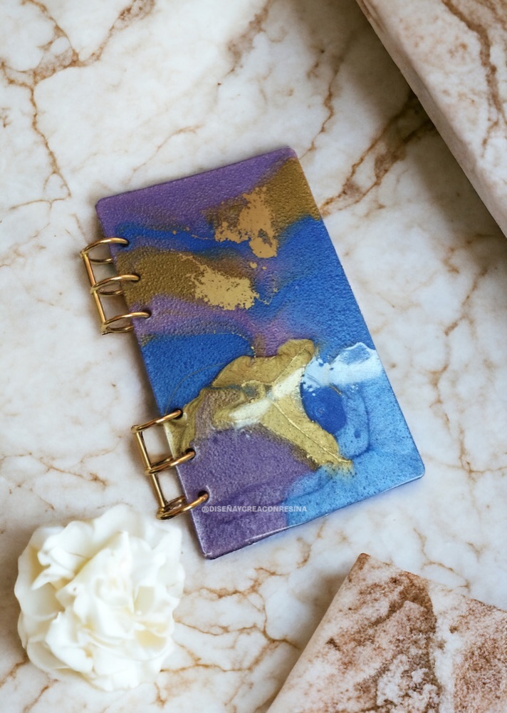 Libreta forrada con resina en tonos azul y dorado, hecha a mano.