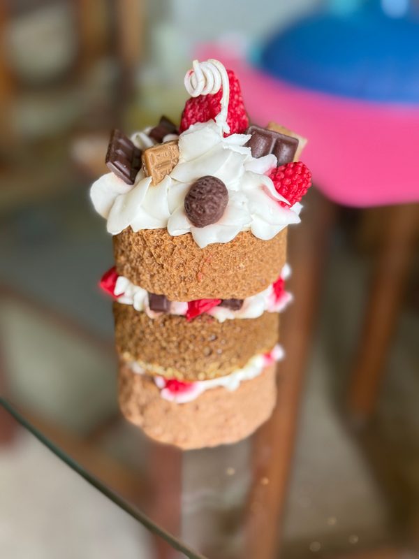 Vela artesanal tipo pastel de varios pisos con crema y fresas.